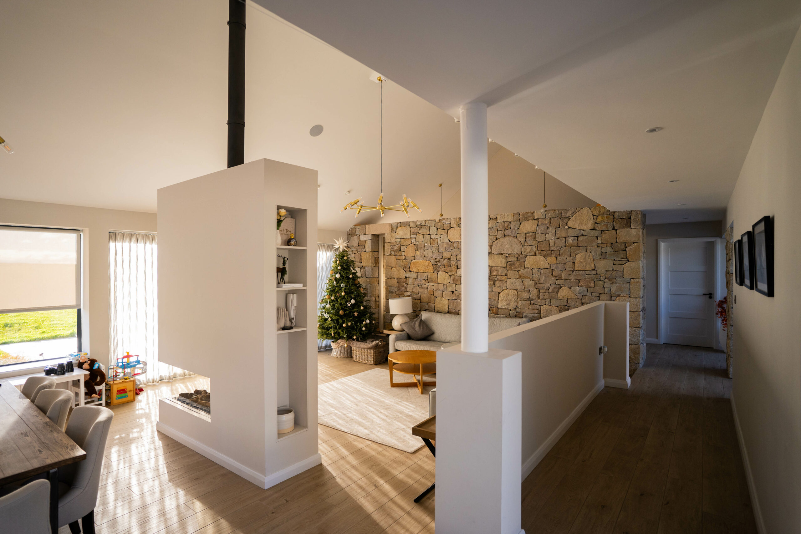 Wide angle view of open plan living area, showing stone wall